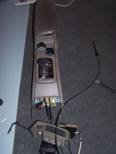 1999 Mercury Grand Marquis - The center console and gear shifter assembly have been removed from the vehicle, exposing internal wiring and components.