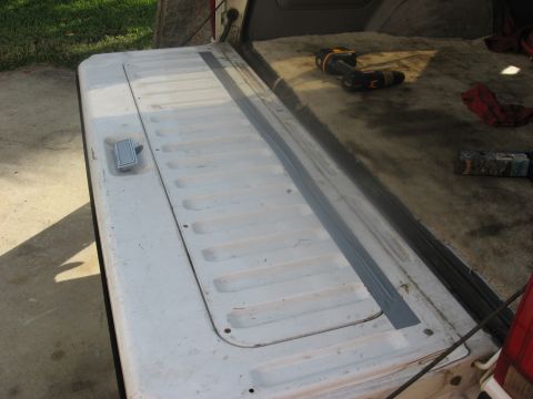 1994 Ford Bronco - Interior view of a vehicle's tailgate, showing the handle and carpeted cargo area with tools.