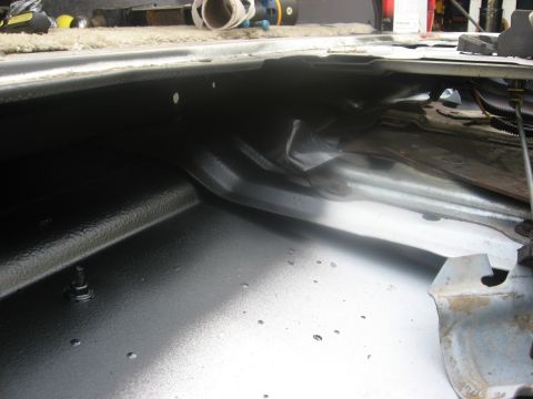 1994 Ford Bronco - The interior of a vehicle's cargo area shows a black textured coating and some exposed metal components.