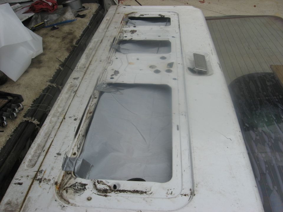 White tailgate with multiple window cutouts, some covered with plastic. Handle visible on right side
