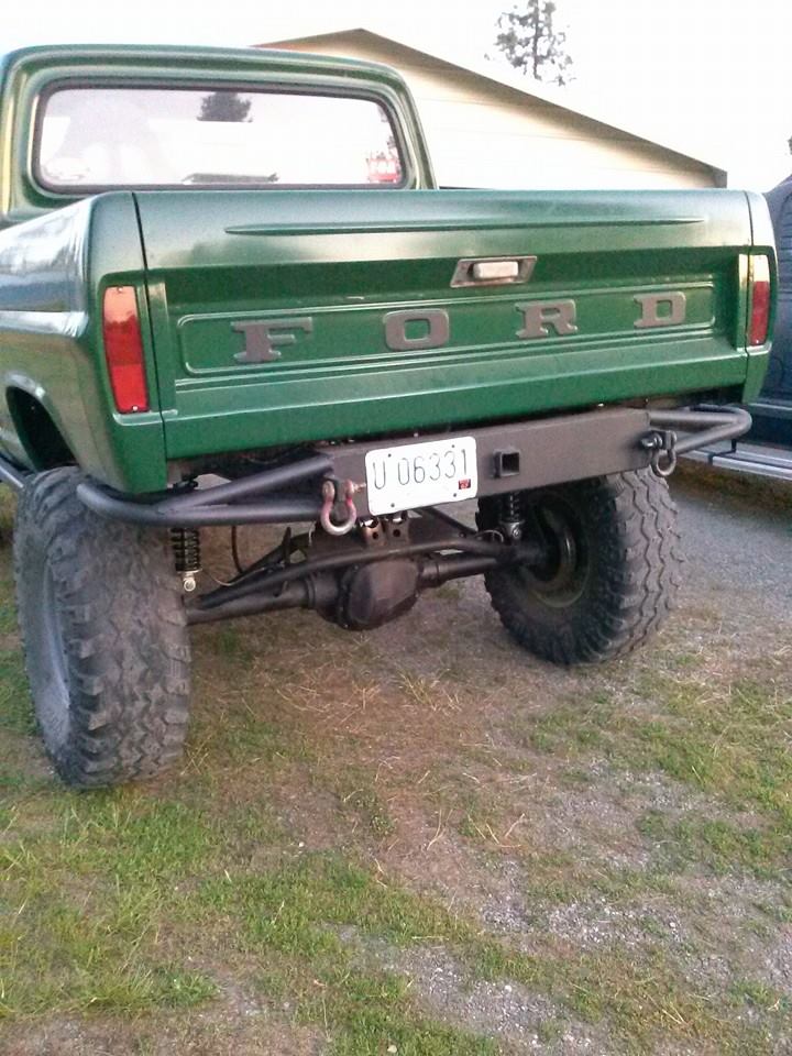 Green Ford pickup truck rear end with custom bumper and large tires. License plate U 06331 is visible