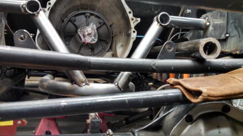 1967 Ford F-250 - Custom fabrication work is underway on a vehicle's chassis, focusing on the transmission and roll cage components.