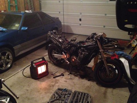 1998 Suzuki Bandit - A motorcycle is partially disassembled in a garage next to a blue car and a portable heater.