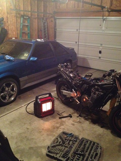1998 Suzuki Bandit - A motorcycle is partially disassembled in a garage, with a blue car parked nearby and a portable heater warming the space.