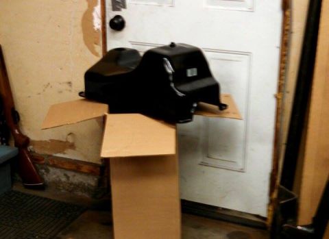 1967 Ford F-250 - A black plastic automotive part is placed on a cardboard box in front of a white door.