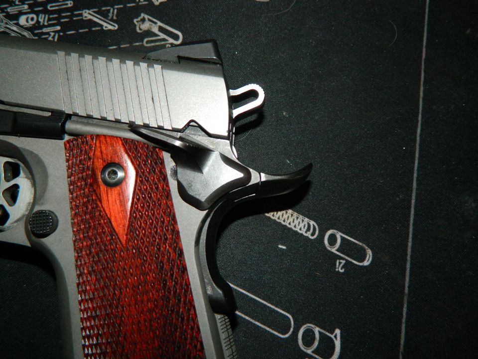 Close-up of a pistol's checkered wood grip and silver slide