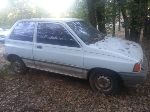 1991 Ford Festiva - This white hatchback appears to be from the early 1990s, with a boxy design and tinted windows.