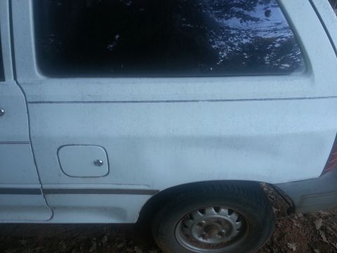 1991 Ford Festiva - Side profile of a white 1991 Ford Festiva, focusing on the rear wheel and fuel door.