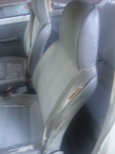 1991 Ford Festiva - The interior of a car shows worn seats and visible seatbelts.