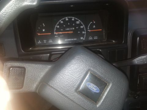 1991 Ford Festiva - The dashboard of a car shows the odometer reading 140,197 miles and a Ford emblem on the steering wheel.