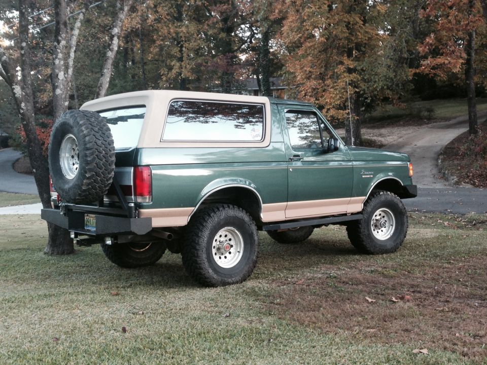 1989 Ford Bronco rear passenger side view, green with tan top, spare tire on rear bumper.