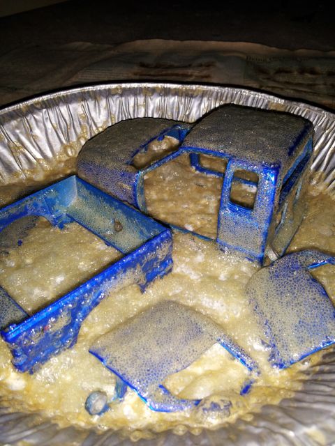 1995 Ford Bronco - Toy truck parts are soaking in a foamy solution within a foil pan.