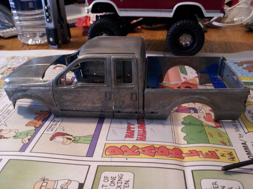 Unpainted model truck body, side view. Another model vehicle is visible behind it