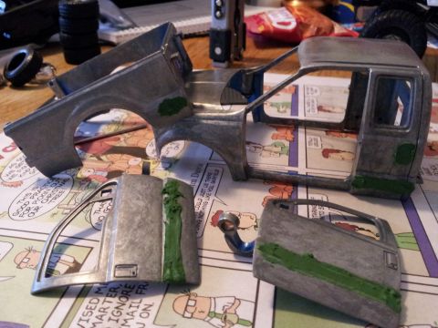 1995 Ford Bronco - Model truck parts are disassembled and laid out on a surface covered with comic strips.