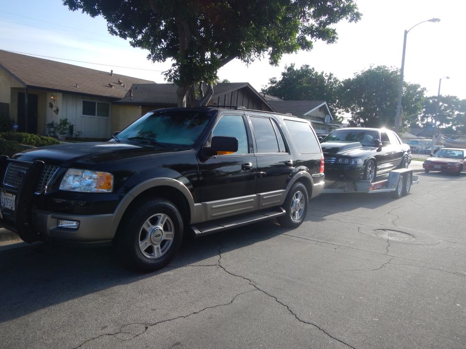 Front three-quarter of black Ford Expedition towing a sedan on trailer