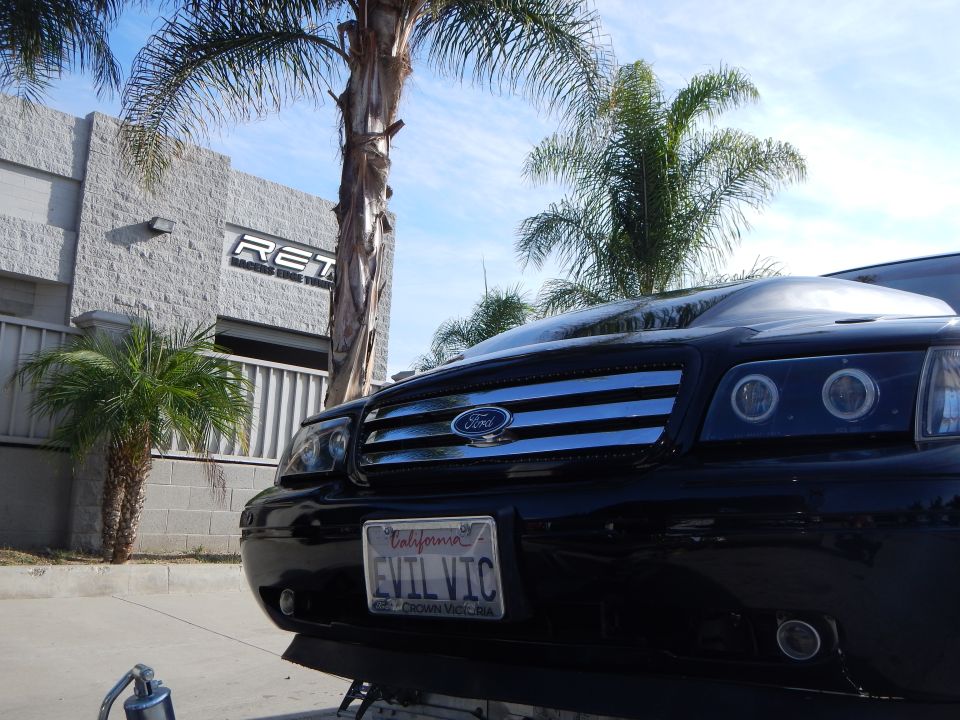 Front grille of a black Ford sedan with halo headlights and EVIL VIC California plate