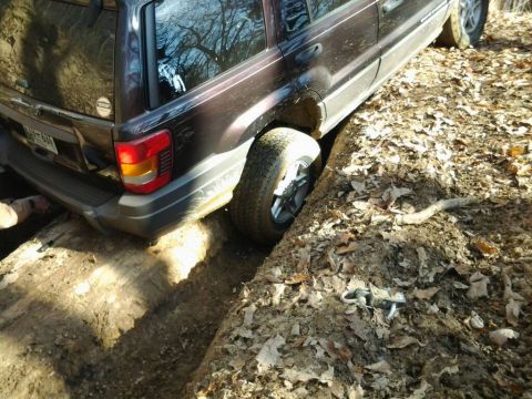 1995 Ford Bronco - This Jeep Grand Cherokee is stuck with its front wheel on a log and rear wheel in a ditch.