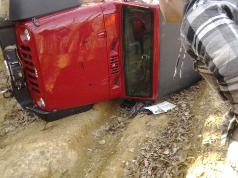 1995 Ford Bronco - Red Jeep Wrangler rolled over in a ditch on a dirt trail.