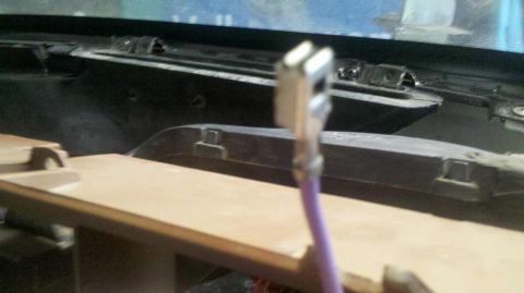 1982 Ford Bronco - A close-up view of a purple wire with a metal connector attached, extending from a tan dashboard component. The background shows a dark, te…