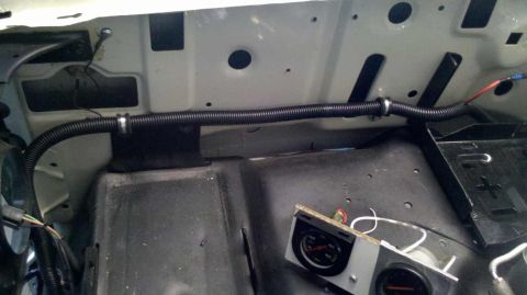 1982 Ford Bronco - A close-up view of the engine bay area of a vehicle, showing black corrugated tubing secured with clamps and running across the firewall. T…