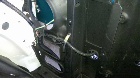 1982 Ford Bronco - A black corrugated conduit with wiring runs along a black metal bracket in what appears to be an engine bay. A white fender is visible on t…