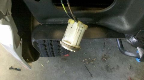1982 Ford Bronco - A close-up view shows a white plastic electrical connector with yellow tape and wires attached, hanging from a black metal bracket. The con…