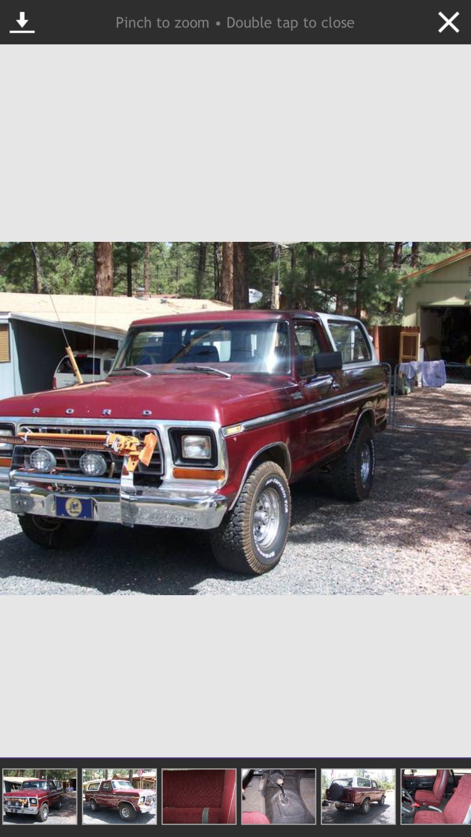 1979 Ford Bronco with fishing rods on the front grille, parked outdoors.