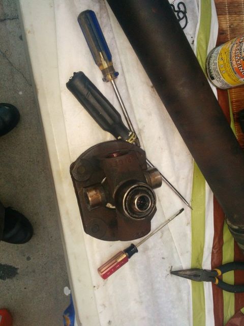 1988 Ford Bronco - A close-up view of a U-joint assembly, along with several tools including screwdrivers and pliers, laid out on a white cloth next to a dark…