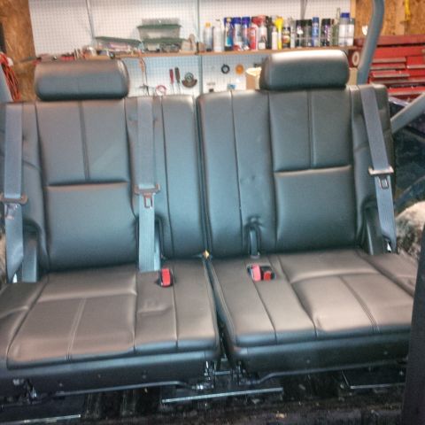 1978 Ford Bronco - A pair of black leather car seats with gray seatbelts are installed in a garage setting. The seats appear to be from a truck or SUV, with v…