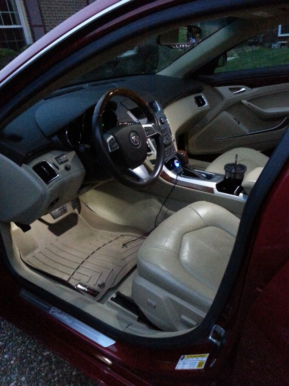Interior of a red Cadillac sedan, showing tan leather seats, dashboard, steering wheel, and center console