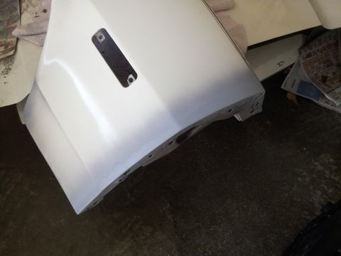 1976 Ford Ranchero - A white car door is shown from a low angle, with a black rectangular cutout in the center. The door appears to be prepped for painting, wit…