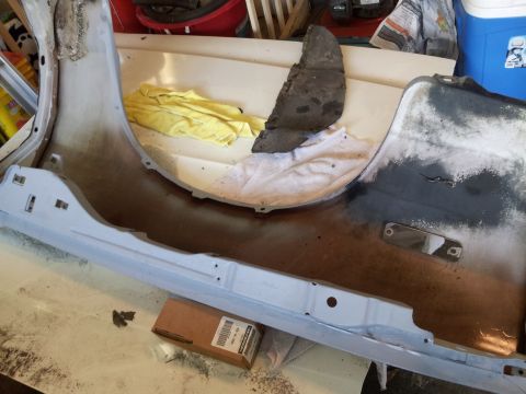 1976 Ford Ranchero - A close-up view of a vehicle's undercarriage or body panel, possibly a fender or bumper, showing primer and some rust. A yellow cloth and a…