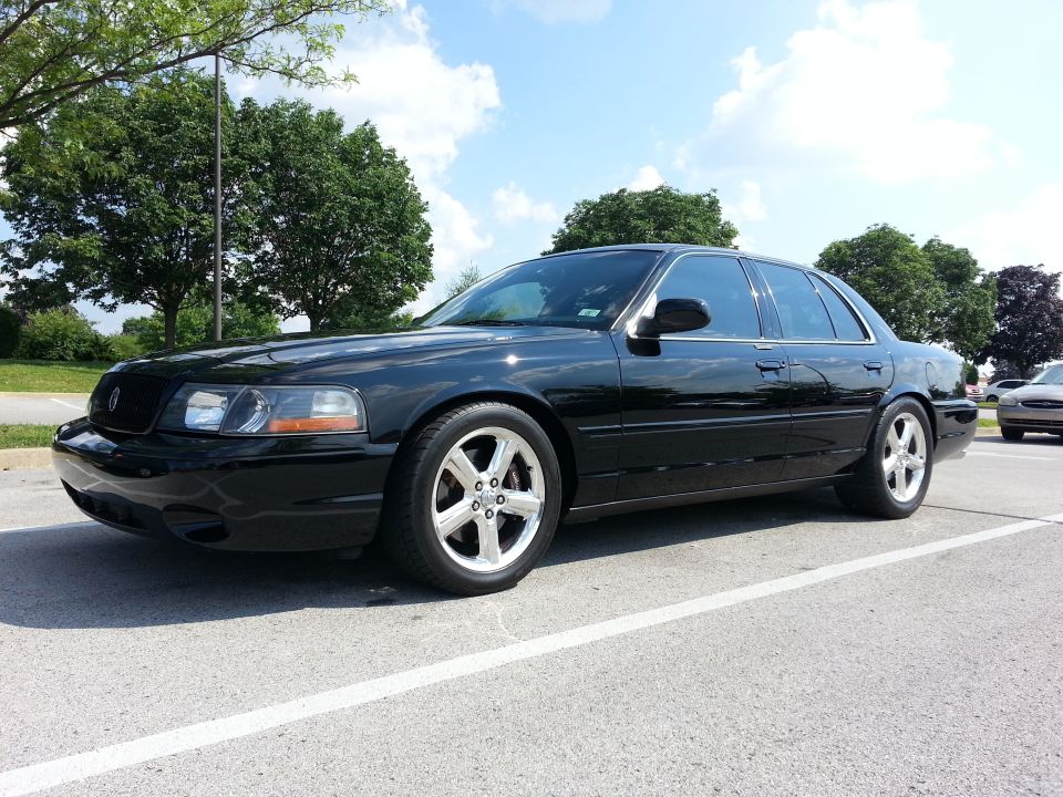 Black four-door sedan with chrome wheels parked in a lot.