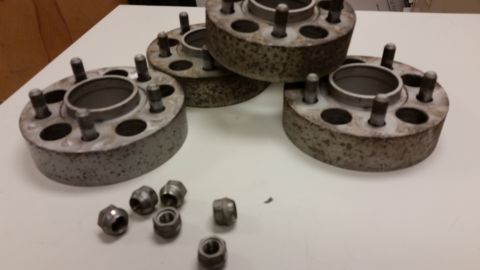 2001 Ford Crown Victoria - Photograph of wheel spacer adapters with bolts and lug nuts on a workbench, not a technical document.