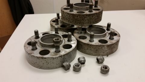 2001 Ford Crown Victoria - Photograph of stacked wheel spacer adapters and loose lug nuts on a table, not a technical document.