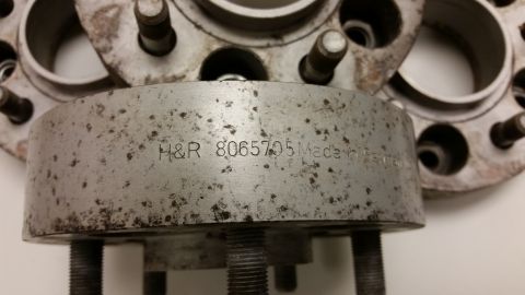 2001 Ford Crown Victoria - Close-up photograph of an H&R wheel spacer with stamped markings on the edge, not a technical document.