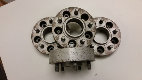 2001 Ford Crown Victoria - Photograph of three wheel spacer adapters stacked on a table, not a technical document.