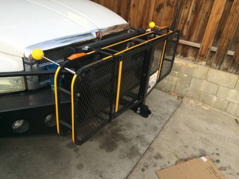 1997 Dodge 3500 - A black cargo carrier with yellow accents is mounted to the front of a white truck. The carrier is attached to a black bull bar and has a m…