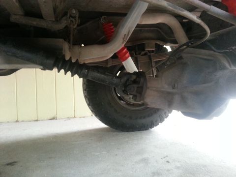 1995 Ford Bronco - The underside of a 1995 Ford Bronco shows the rear differential, driveshaft, leaf springs, and a red shock absorber. The vehicle is parked…