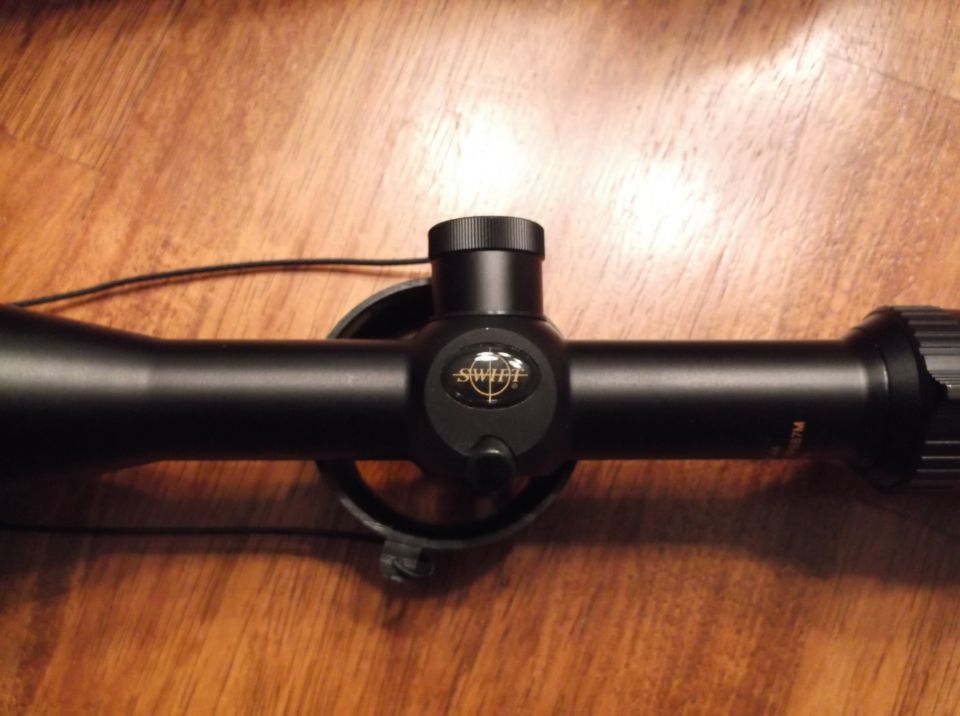 Black rifle scope with SWIFT logo on a wooden surface.