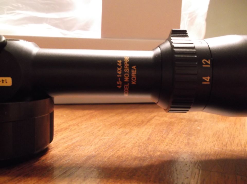 Black rifle scope with magnification numbers 14 and 12, and model information.