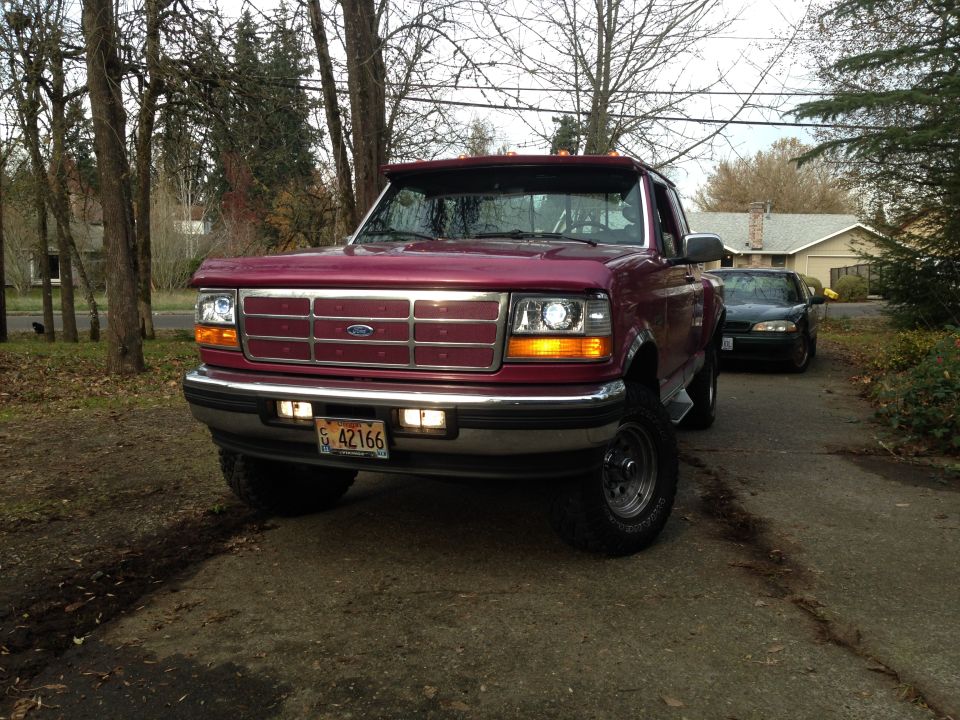 Dark red 1990s Ford F-150 pickup truck front view, parked on driveway.
