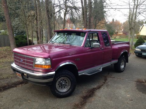 1992 Ford F-150 - Three-quarter driver's-side front view of a raspberry-magenta ninth-generation Ford F-Series extended-cab 4x4 pickup on a wet driveway amon…