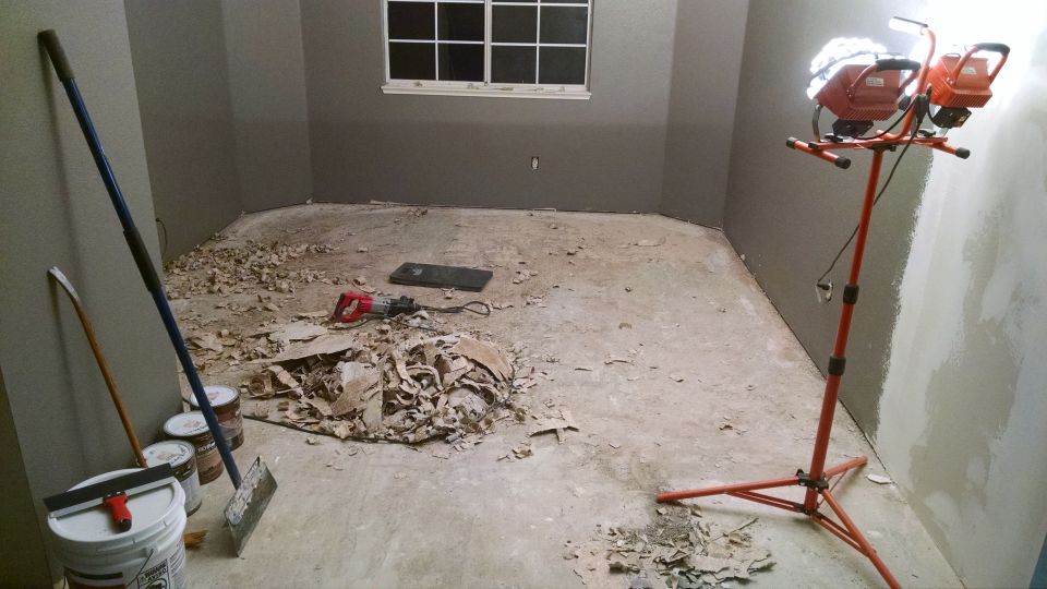 Room renovation scene with debris, tools, and a work light.