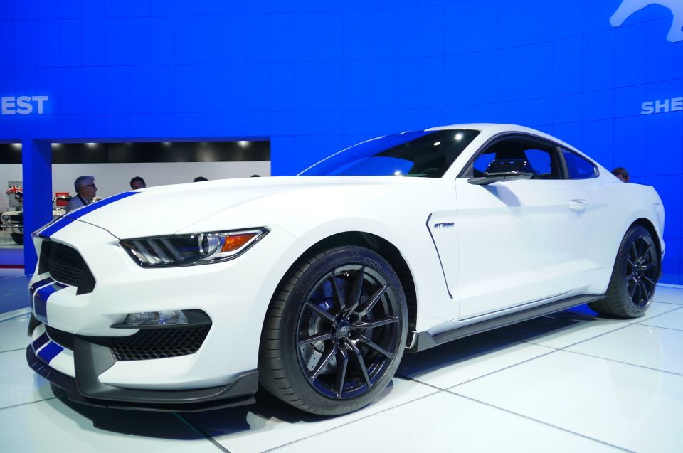 White Ford Mustang GT350 with blue stripes, front 3/4 view.