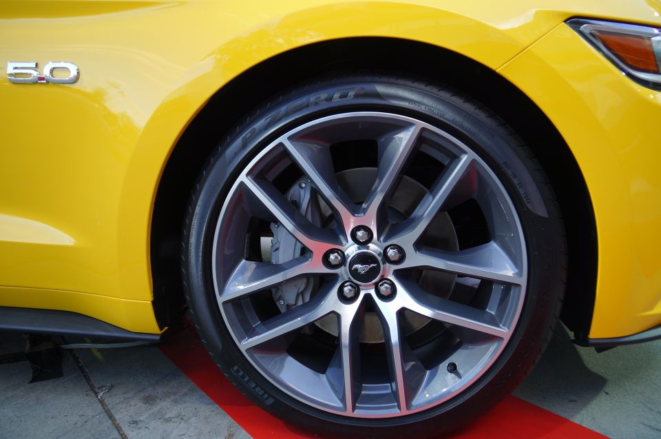 Yellow Ford Mustang front wheel and fender with 5.0 badge.