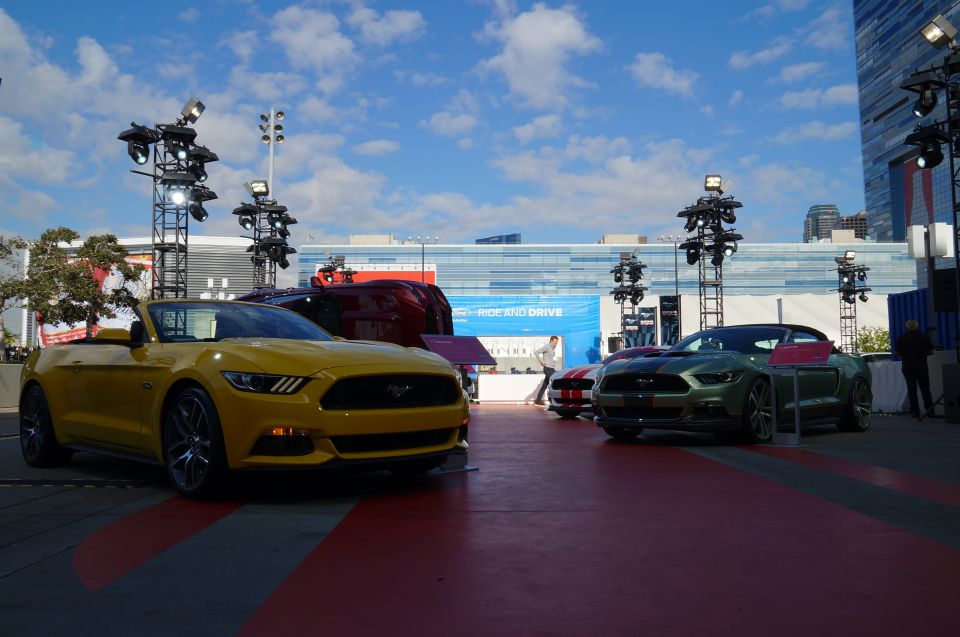 Yellow and green convertible sports cars on display with a building and sky in the background.