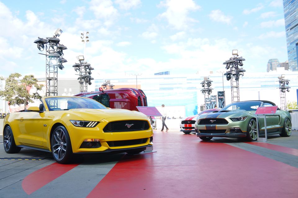 Yellow convertible Mustang in foreground, green convertible Mustang with racing stripes in background.