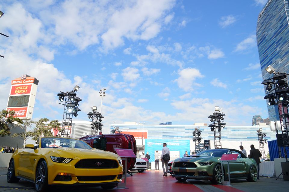 Yellow convertible Ford Mustang parked on a red carpet with Staples Center in the background.