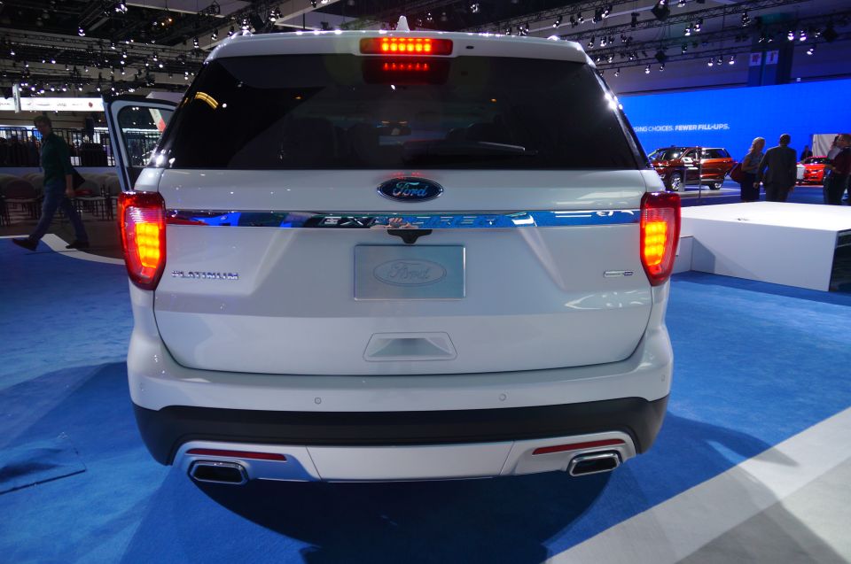 Rear view of a white Ford Explorer Platinum SUV with taillights on.